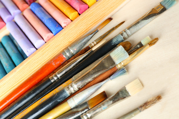 Paintbrushes with colorful chalk pastels in box on fabric background - Photo, Image
