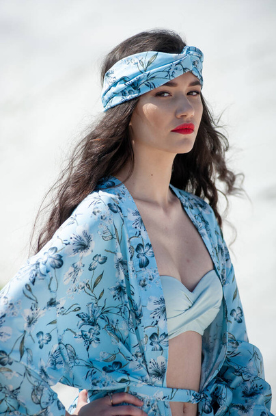 beautiful young woman in a white dress and a blue scarf on the beach - Photo, Image