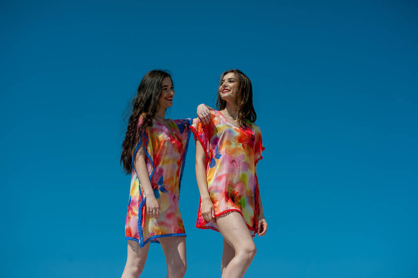 belle giovani donne con un trucco luminoso e una ragazza in un vestito rosso sulla spiaggia - Foto, immagini