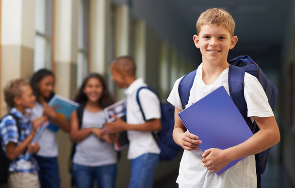Готов к школе. Портрет счастливого школьника, стоящего в коридоре со своими друзьями на заднем плане - Фото, изображение
