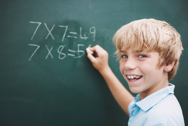 Excited about doing his sums. A young boy doing his sums on a blackboard with a piece of chalk - copyspace - Foto, Imagem