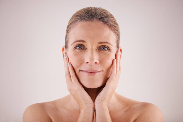 Portrait, senior woman and face for cosmetic wellness or touching her perfect skin or isolated and on grey background. Mature lady, massaging wrinkles and facial aging or dermatology and skincare. - Foto, Imagen