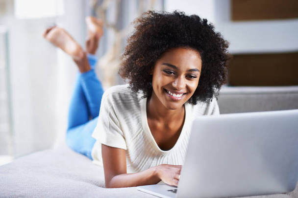 Smile, relax and woman with a laptop, typing and connection for movies, social media and online reading. Female person, happy lady and girl with happiness, technology and chatting at home. - Photo, Image
