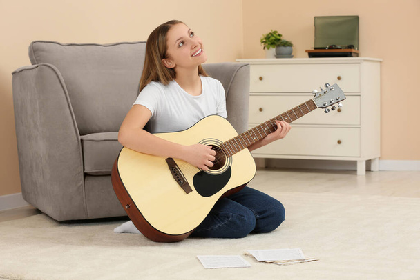 Teenage girl playing acoustic guitar in room - Φωτογραφία, εικόνα