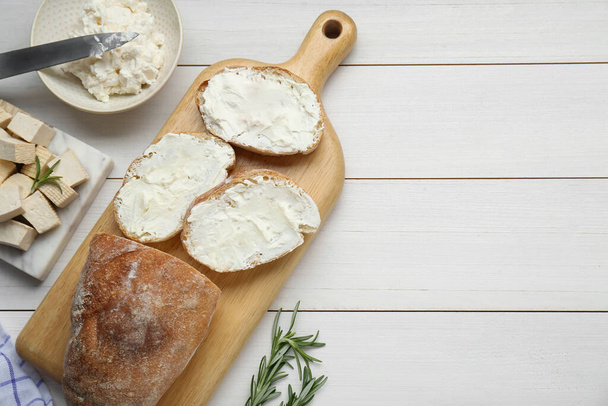 Slices of baguette with tofu cream cheese and rosemary on white wooden table, flat lay. Space for text - Zdjęcie, obraz