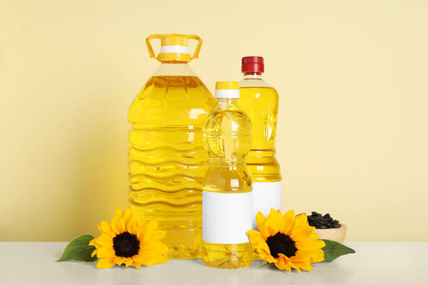 Bottles of cooking oil, sunflowers and seeds on white table - Foto, immagini