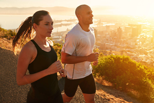 Sunrise, training and running couple as workout or morning exercise for health and wellness together. Sport, athlete and woman runner run with man as fitness in a city for sports or energy. - Фото, изображение