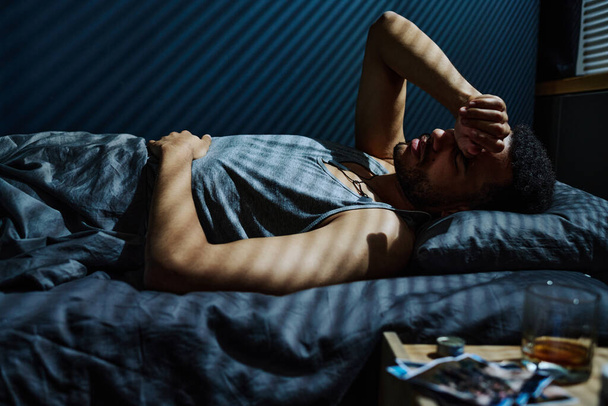 Jonge man in de problemen blijven de hele nacht niet in staat om in slaap te komen terwijl herinneren traumatische gebeurtenis die PTSS veroorzaakt - Foto, afbeelding
