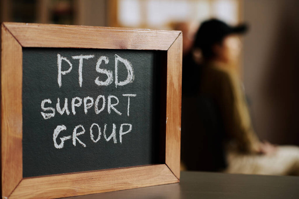 Μικρό chalkboard με το όνομα της ομάδας ψυχολογικής υποστήριξης ή μάθημα σε ξύλινο πλαίσιο στέκεται ενάντια στους συνοδούς της συνεδρίας - Φωτογραφία, εικόνα