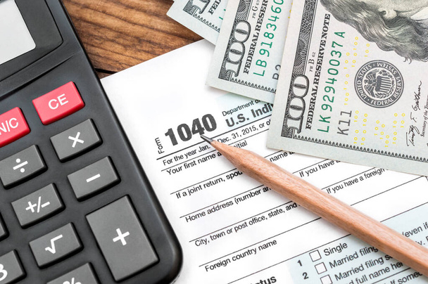 Налоговая форма 1040 с карандашом, деньгами и калькулятором на столе. Бизнес-концепция. Вид сверху. - Фото, изображение