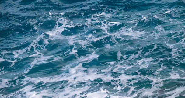 Zeewater achtergrond. Blauwe zee textuur met golven en schuim. - Foto, afbeelding
