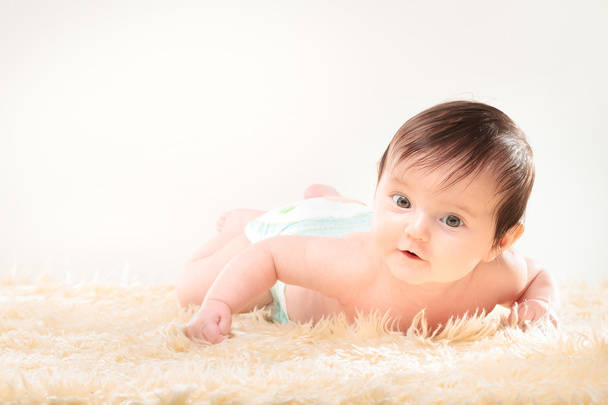 毛皮で覆われた毛布の上に横たわる女の赤ちゃん - 写真・画像