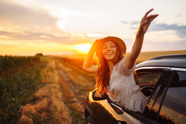 Young woman is resting and enjoying sunset in the car. Summer trip. Lifestyle, travel, tourism, nature, active life. - Fotoğraf, Görsel
