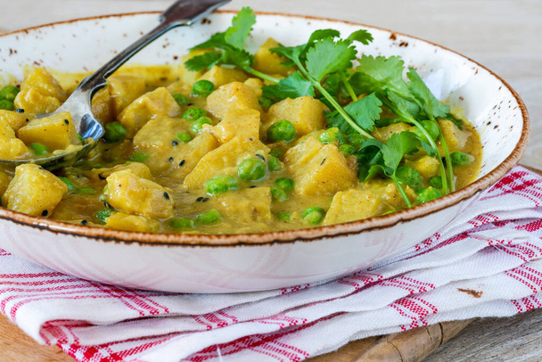 Coconut and potato curry with green peas - Foto, afbeelding