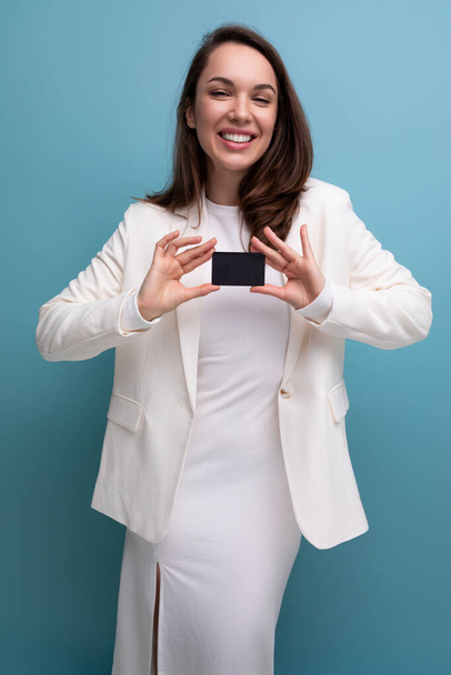 μελαχρινή γυναίκα σε ένα φόρεμα χρησιμοποιεί ηλεκτρονική μεταφορά χρημάτων χρησιμοποιώντας μια κάρτα και ένα smartphone. - Φωτογραφία, εικόνα