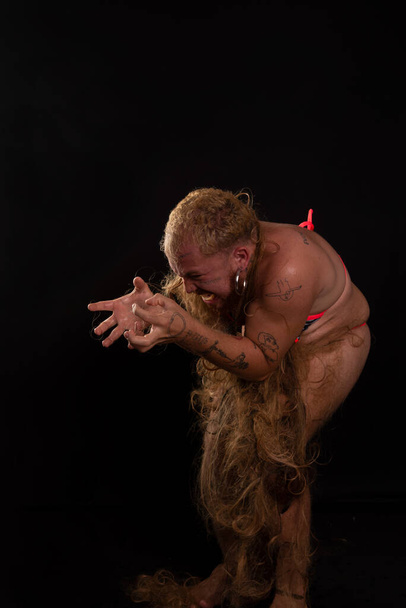 Молодий чоловік-актор виконує жіночу горилку з волоссям по всьому тілу і вираженням болю. ізольовані на темному фоні
. - Фото, зображення