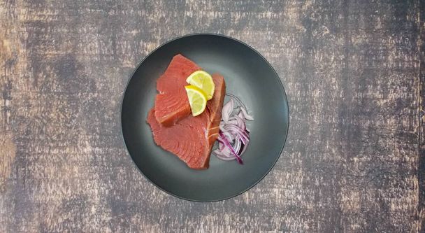 kékúszójú tonhal frissen - előkészítésre készen - sötét háttérrel és fekete tányérral - Fotó, kép