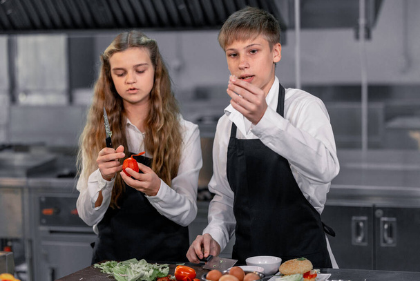 Teenagers learn from expert chefs at culinary school to prepare ingredients and create a variety of tasty meals. A practical activity connected their senses of taste and smell is making hamburgers. - Foto, Bild