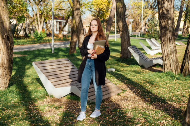 Desafíos de salud mental que enfrentan los estudiantes universitarios. Retrato franco de una joven estudiante con portátil y libros al aire libre. - Foto, imagen