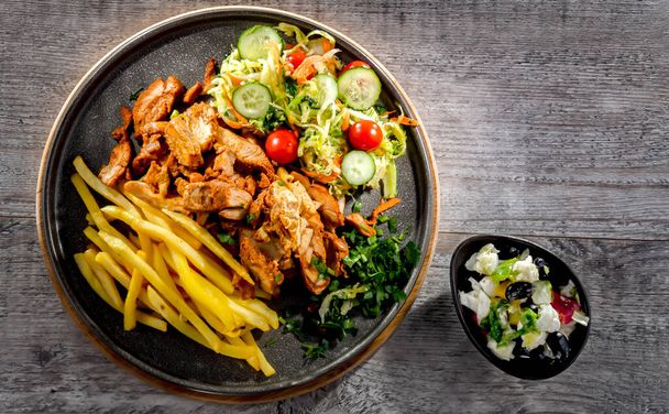 Kebab served with french fries, vegetable salad and tzatziki - Foto, afbeelding