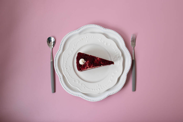 Torta di velluto rosso su piatto di ceramica bianca, sfondo rosa, vista dall'alto - Foto, immagini