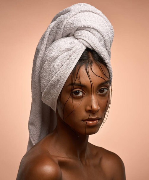 Wrapped up in the pleasures of the world. Portrait of a beautiful young woman with her hair wrapped in a towel against a brown background - Fotografie, Obrázek