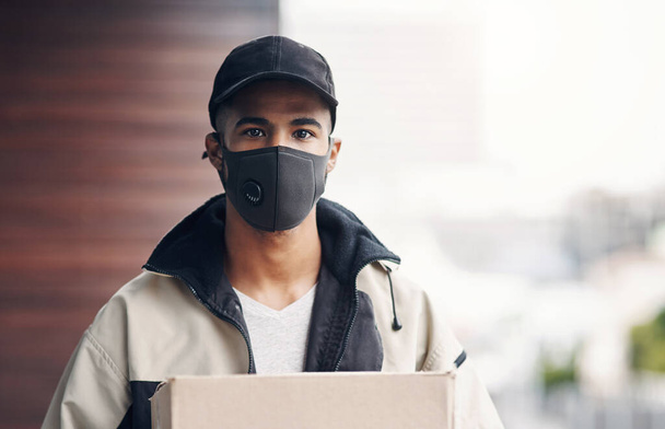 Obchod s doručováním domů vzkvétá. maskovaný mladý muž doručující balíček na místo bydliště - Fotografie, Obrázek