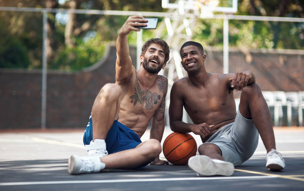 Товарищи по команде, которые стали лучшими друзьями. два спортивных юноши делают селфи на баскетбольной площадке - Фото, изображение