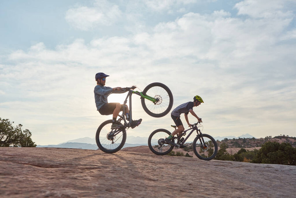 Ты никогда не заскучаешь, когда будешь кататься на горном велосипеде. Длинный снимок двух мужчин, катающихся на горном велосипеде вместе в течение дня - Фото, изображение