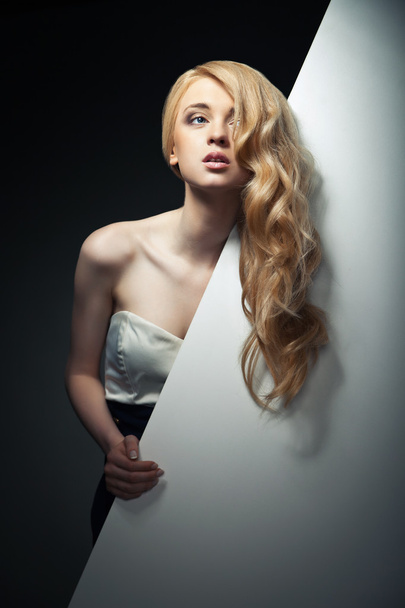 pretty blond model hiding behind a big sheet of paper - Foto, Imagen