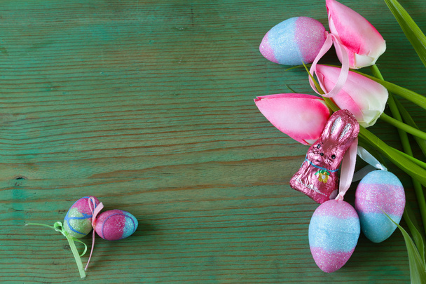 Барвисті декоративні великодні яйця і гілки з весняними квітами на старому дерев'яному фоні
 - Фото, зображення