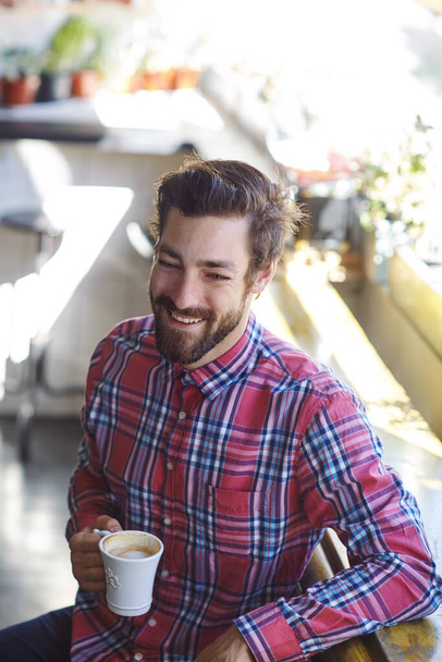 Alimentado por cafeína. um jovem segurando uma xícara de café em um café - Foto, Imagem