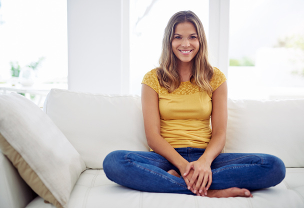 Weekends are for the sofa. Full length portrait of an attractive young woman sitting with her legs crossed on the sofa at home - Fotografie, Obrázek