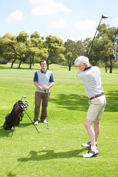 His swing is looking good. Golfing companions out on the course playing a round of golf - Φωτογραφία, εικόνα