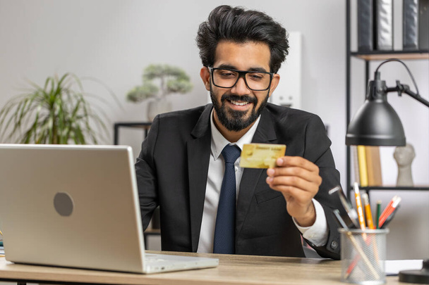 Parrakas liikemies ohjelmoija ohjelmistokehittäjä työskentelee tehdä verkossa ostaa maksu ostoksia luottokortilla ja käyttää kannettavaa kotitoimiston työpöytä kannettavalla tietokoneella. Intialainen freelancer liikemies - Valokuva, kuva