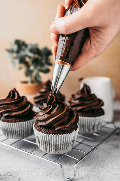 Making and decorating of delicious homemade chocolate cupcakes. Sweet food concept. - 写真・画像