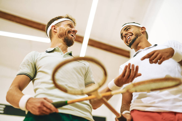 Ik zie je op het Winnaars podium. twee jonge mannen kruisen hun rackets op een squashbaan - Foto, afbeelding