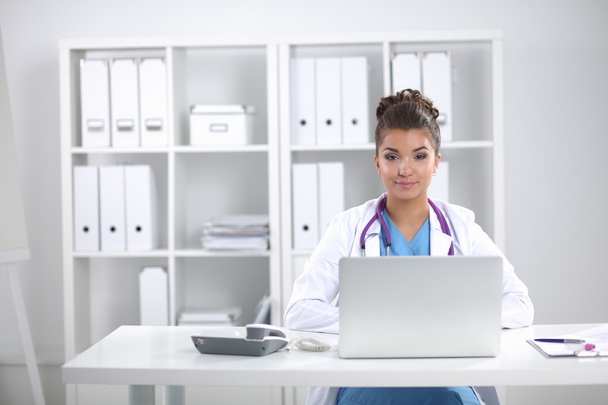 Médica mulher sentada na mesa e trabalhando em um laptop
 - Foto, Imagem