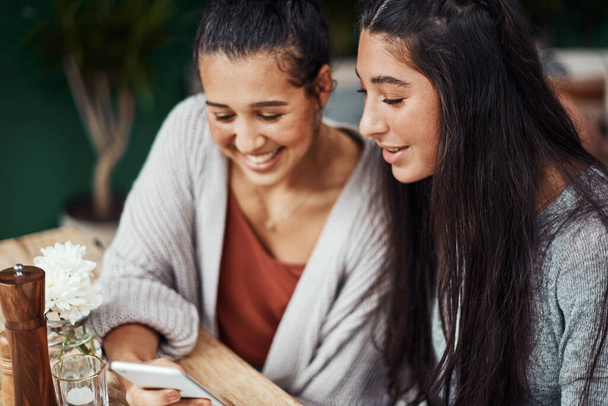 Suurin yhteytemme on tyttöihimme. Nuoret sisaret käyttävät älypuhelinta yhdessä kahvilassa - Valokuva, kuva