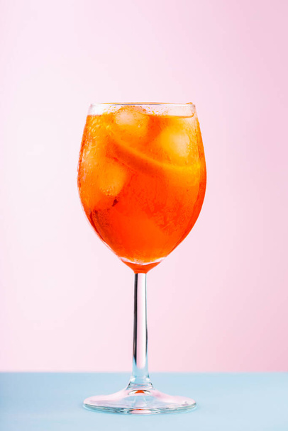 Aperol Spritz cocktail in glass on a pink blue background. Cocktail Aperol Spritz with orange and ice cubes. Close up - Фото, зображення