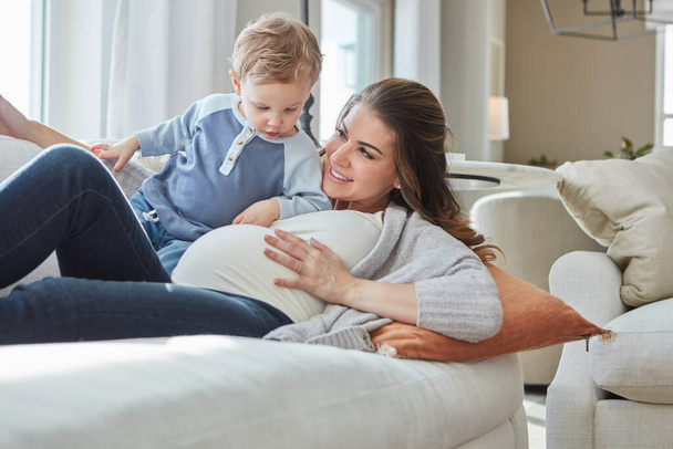 We both love feeling the little one move. a pregnant woman bonding with her toddler son at home - Valokuva, kuva