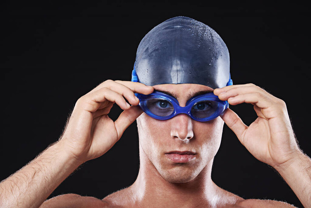 See you in the lane. Studio portrait of a young male swimmer with goggles and cap - Foto, immagini