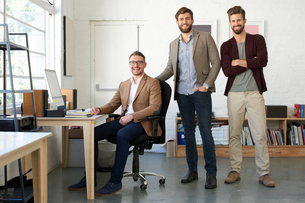 大きな夢のためのソリッドチーム。創造的なオフィススペースで3人の創造的なプロの男性のチーム - 写真・画像