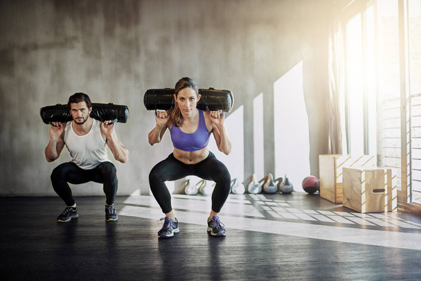Fitness, health and strong with people lifting weighted bags in the gym during a workout for physical power. Exercise, weightlifting or sports with a man and woman bodybuilder training for wellness. - Photo, Image