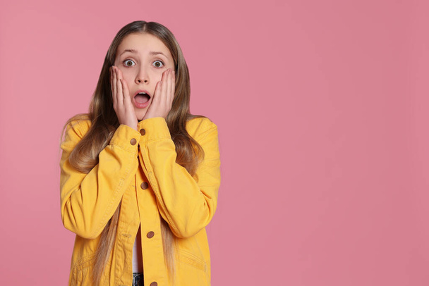 Portrait of shocked teenage girl on pink background. Space for text - Foto, imagen
