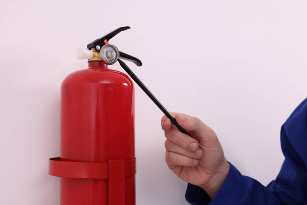 Man checking quality of fire extinguisher indoors, closeup - Foto, imagen
