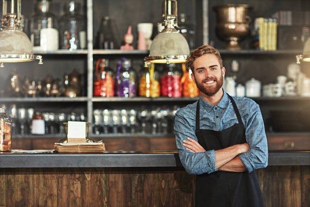 Happy, crossed arms and portrait of male barista standing by the counter in his startup cafeteria. Smile, success and young man small business owner with confidence in coffee shop or restaurant - Photo, image