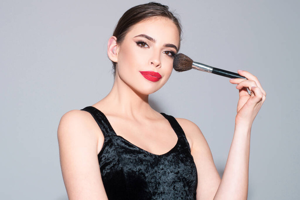 Beautiful woman putting blush with cosmetic brush. Close up face beauty portrait - 写真・画像