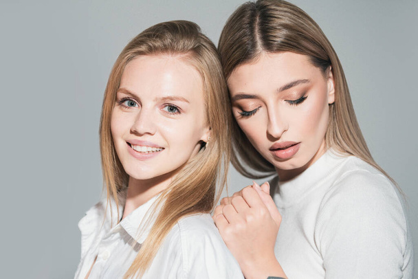 Portrait of two cheerful young women. Two beautiful young women with perfect skin in the studio. Lesbians lgbt couple - Foto, Imagen