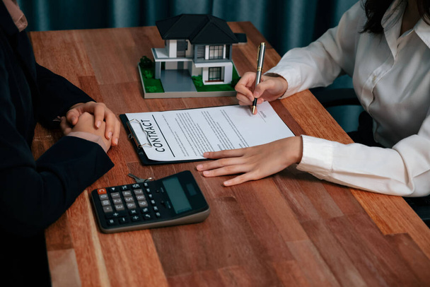 Completando el paso final del proceso de préstamo de la casa, el comprador firma el papel del contrato de préstamo con un bolígrafo en el escritorio, asegurando la propiedad de la propiedad. Entusiasta. - Foto, Imagen